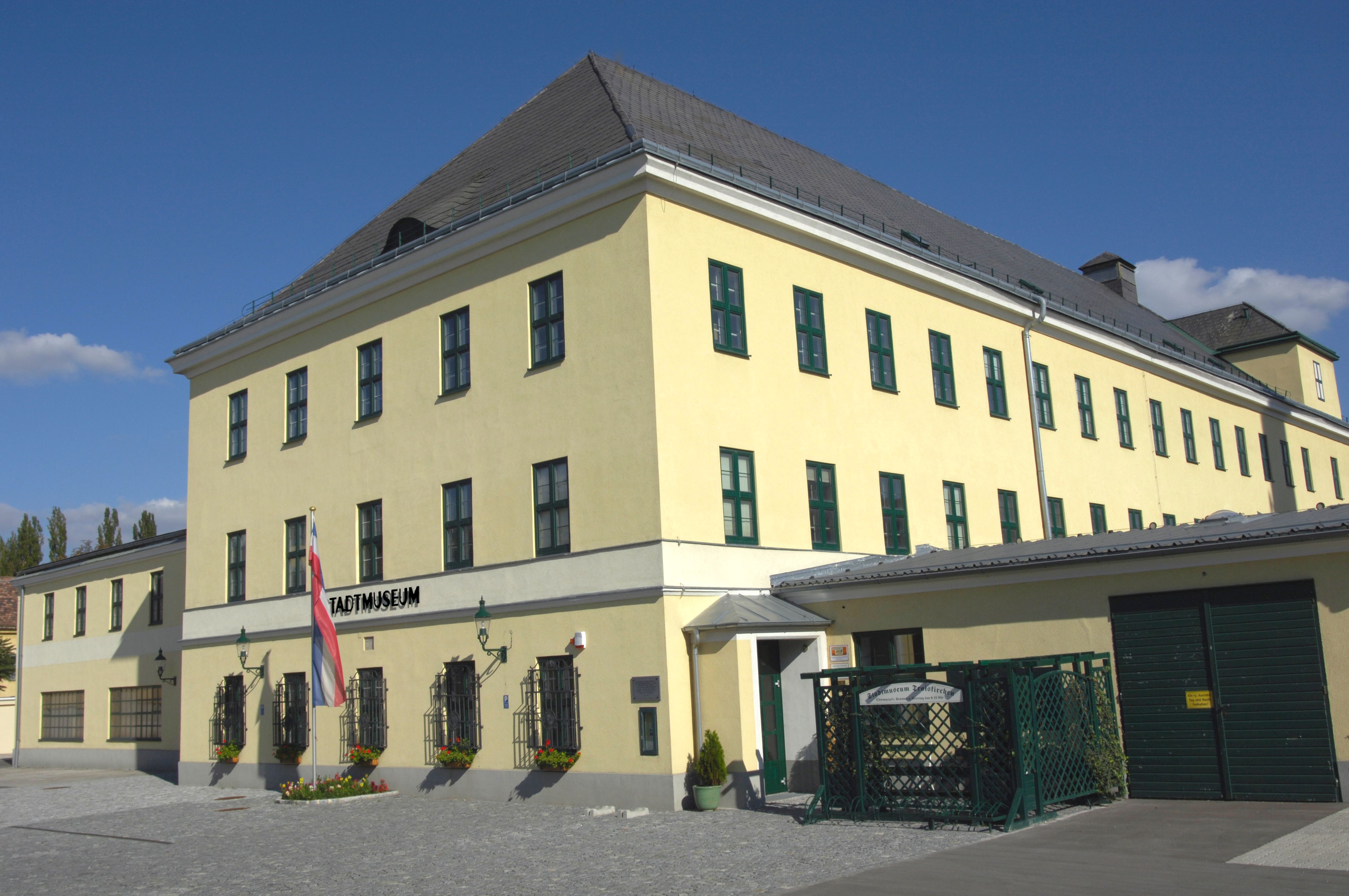Yellow building with the inscription "Stadtmuseum" and an Austrian flag in front of it.