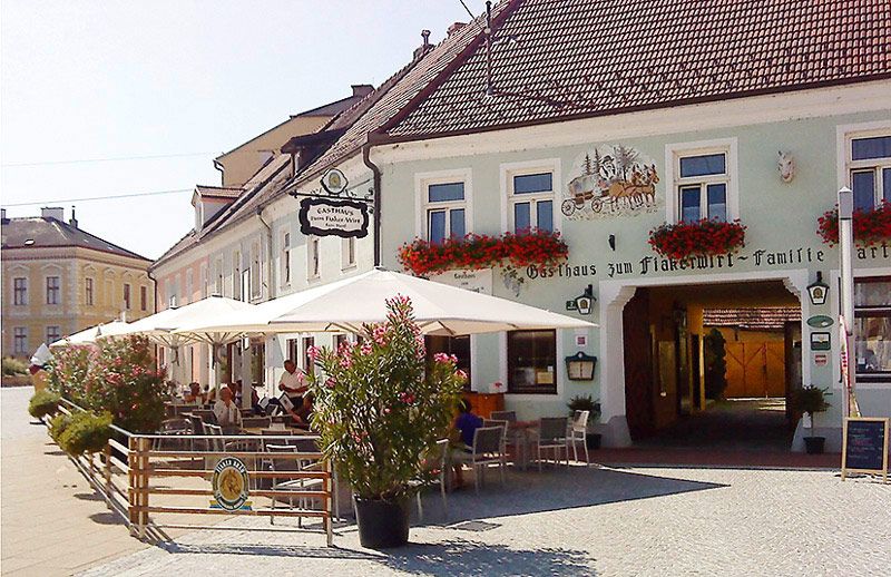 Exterior view of a traditional inn with terrace and parasols.