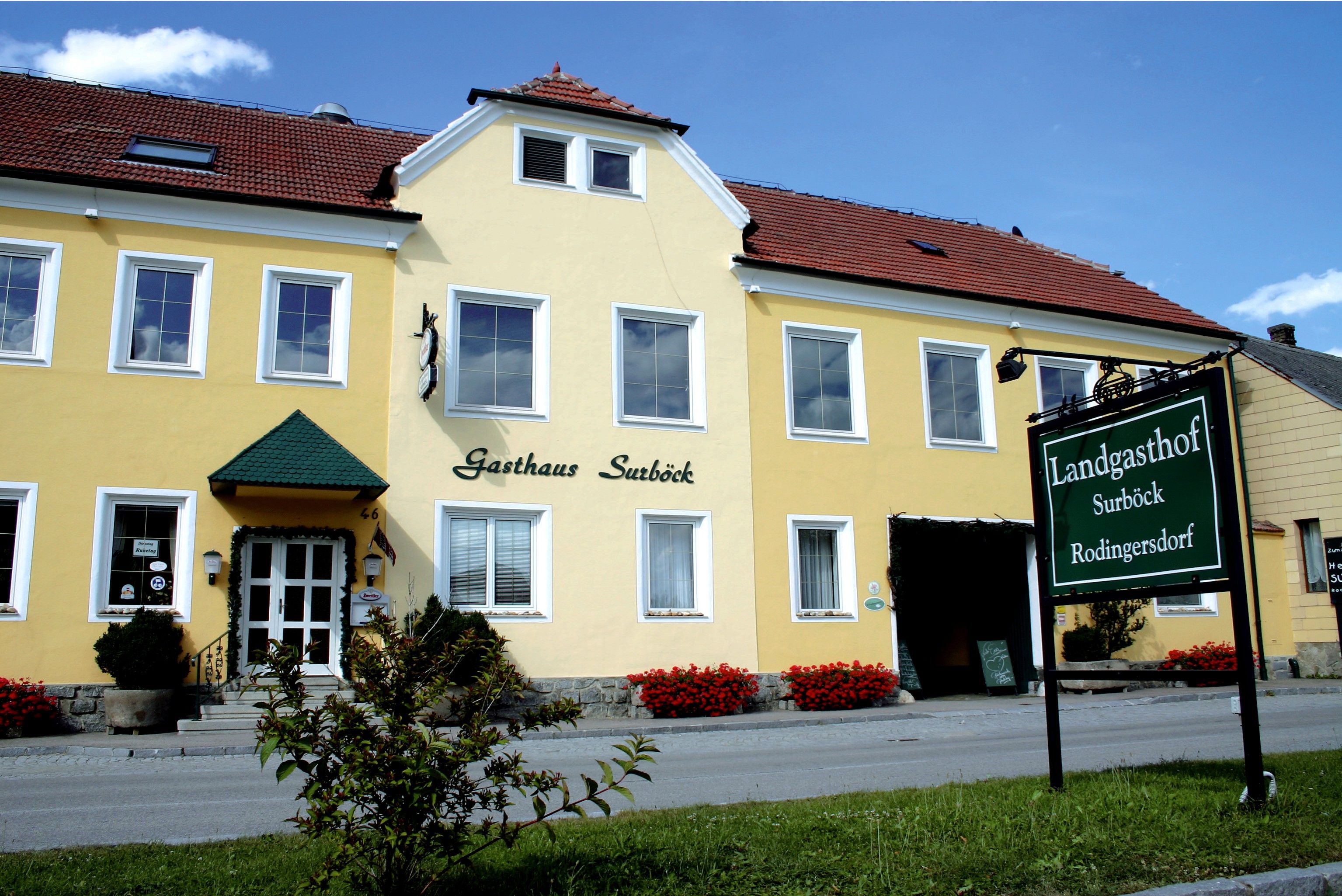 Yellow building with the inscription 'Gasthaus Surböck' and a green sign 'Landgasthof Surböck Rodingersdorf'.
