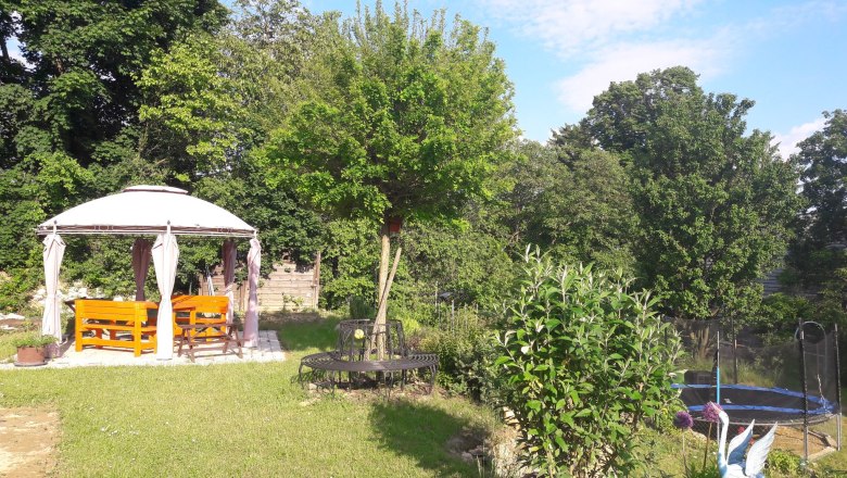 A garden with pavilion, benches, trampoline and trees.