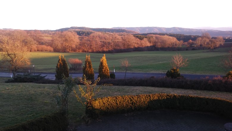 Landscape with meadows, trees and hills at sunset.
