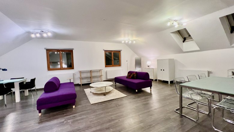 Modern loft with purple sofas, dining table and wooden floor.