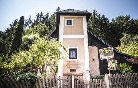 A small tower with a wooden fence and trees in the background.