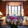 A cozy living room with wood paneling, a window with a view outside and a bouquet of flowers in the foreground.