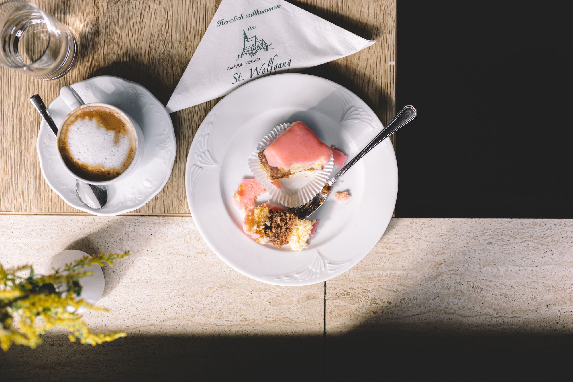 A plate with half a punch doughnut and a cup of coffee on a table.