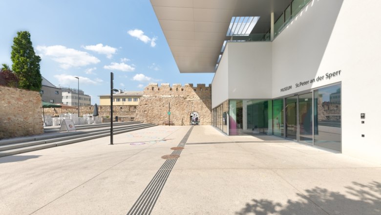 Modern building of the St. Peter an der Sperr Museum with glass façade and historic masonry in the background.