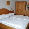 Comfort room with solid wood furniture, double bed, closet and flowers on chest of drawers.