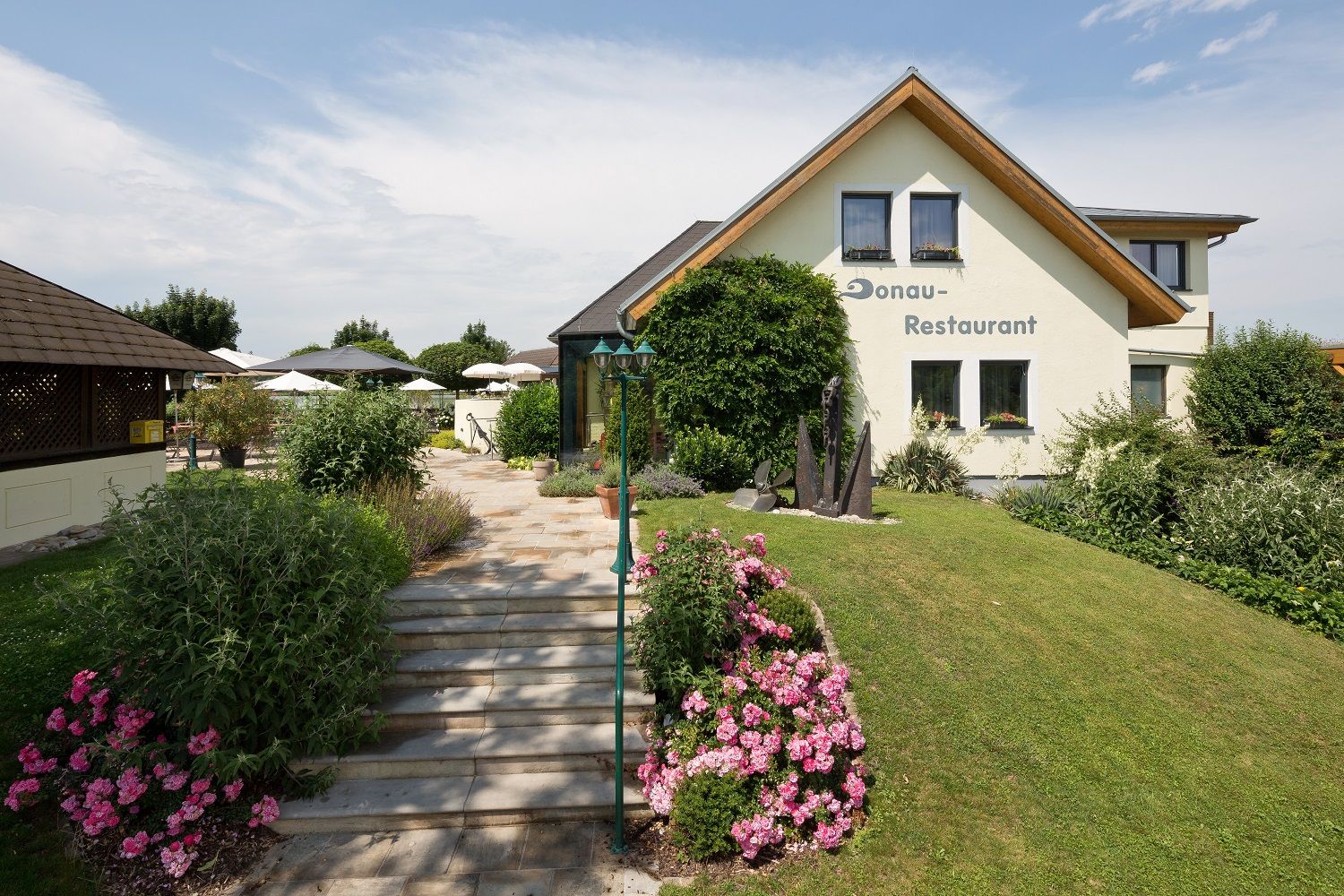 A restaurant with a garden and terrace, surrounded by flowers and bushes.