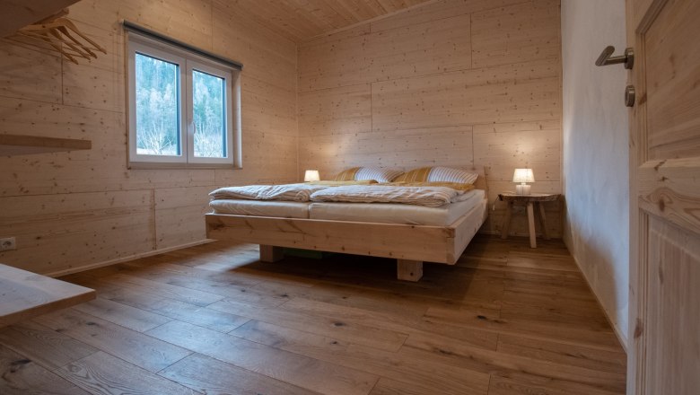 Wood-paneled bedroom with double bed and bedside lamps.
