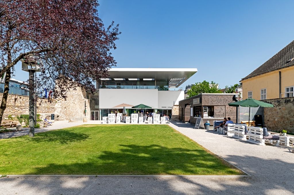 Modern garden with lawn, seating area and buildings in the background.
