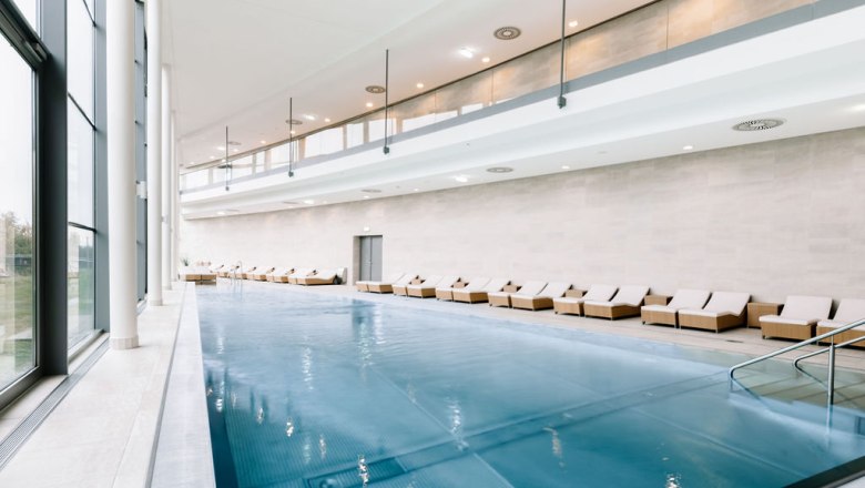 Interior view of a modern spa area with pool and loungers.