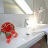 Modern bathroom with washbasin, towel, hairdryer and flower arrangement.