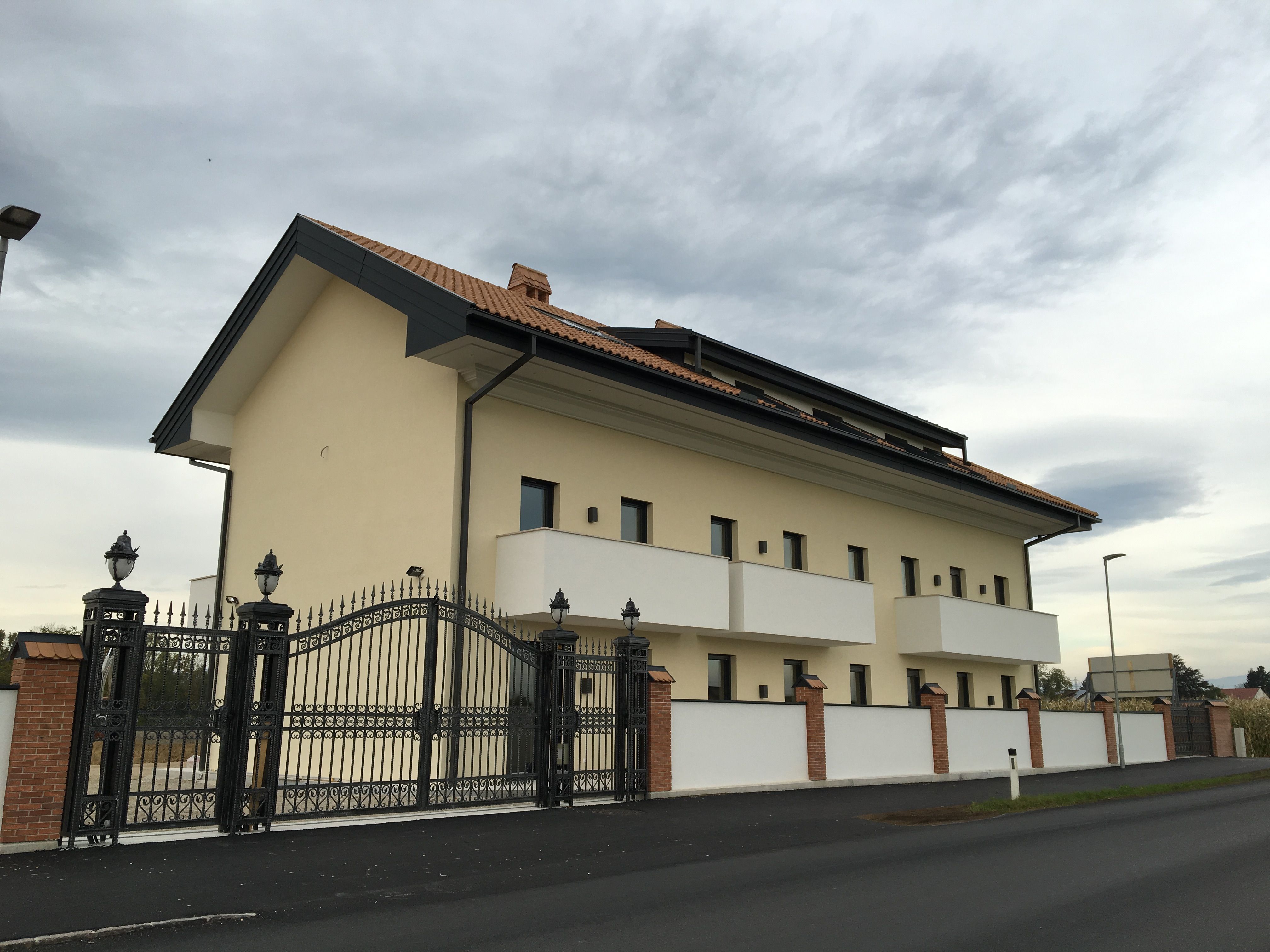Exterior view of a modern building with a tiled roof and wrought-iron gate.