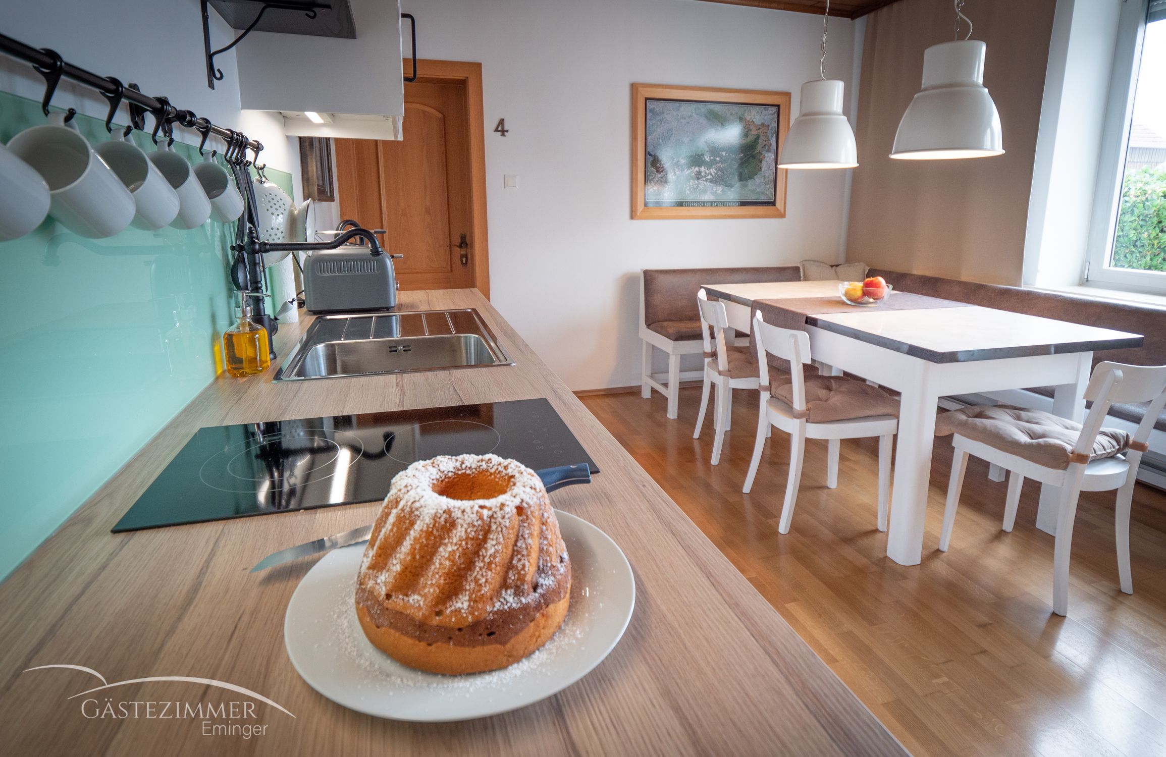 Modern eat-in kitchen with dining table, chairs and Gugelhupf on the worktop.