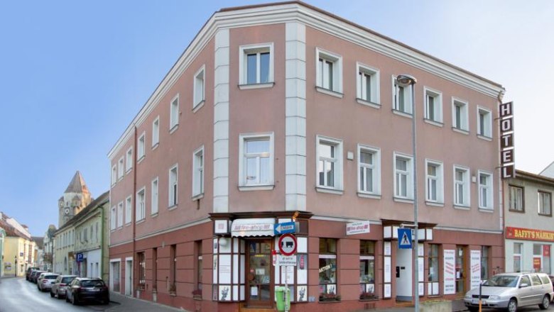 Hotel, © Hotel zu Sonne Three-story hotel building on a street corner with cars and stores.