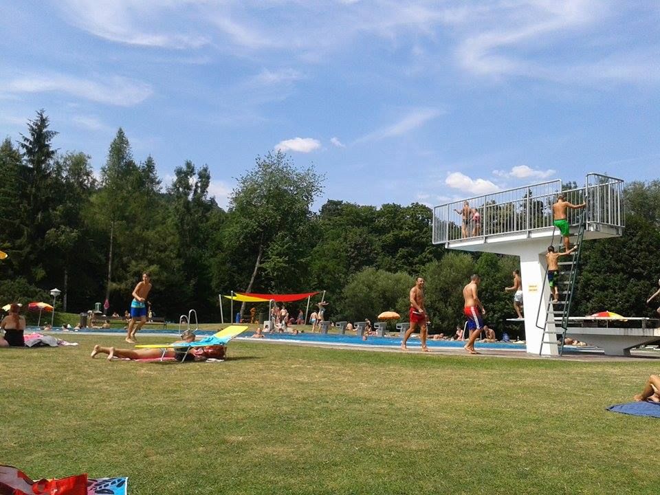 People in the Seebenstein park pool, some on the lawn, others in the pool. A diving tower can be seen.