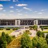 Exterior view of the Therme Laa Hotel with green garden and blue sky.