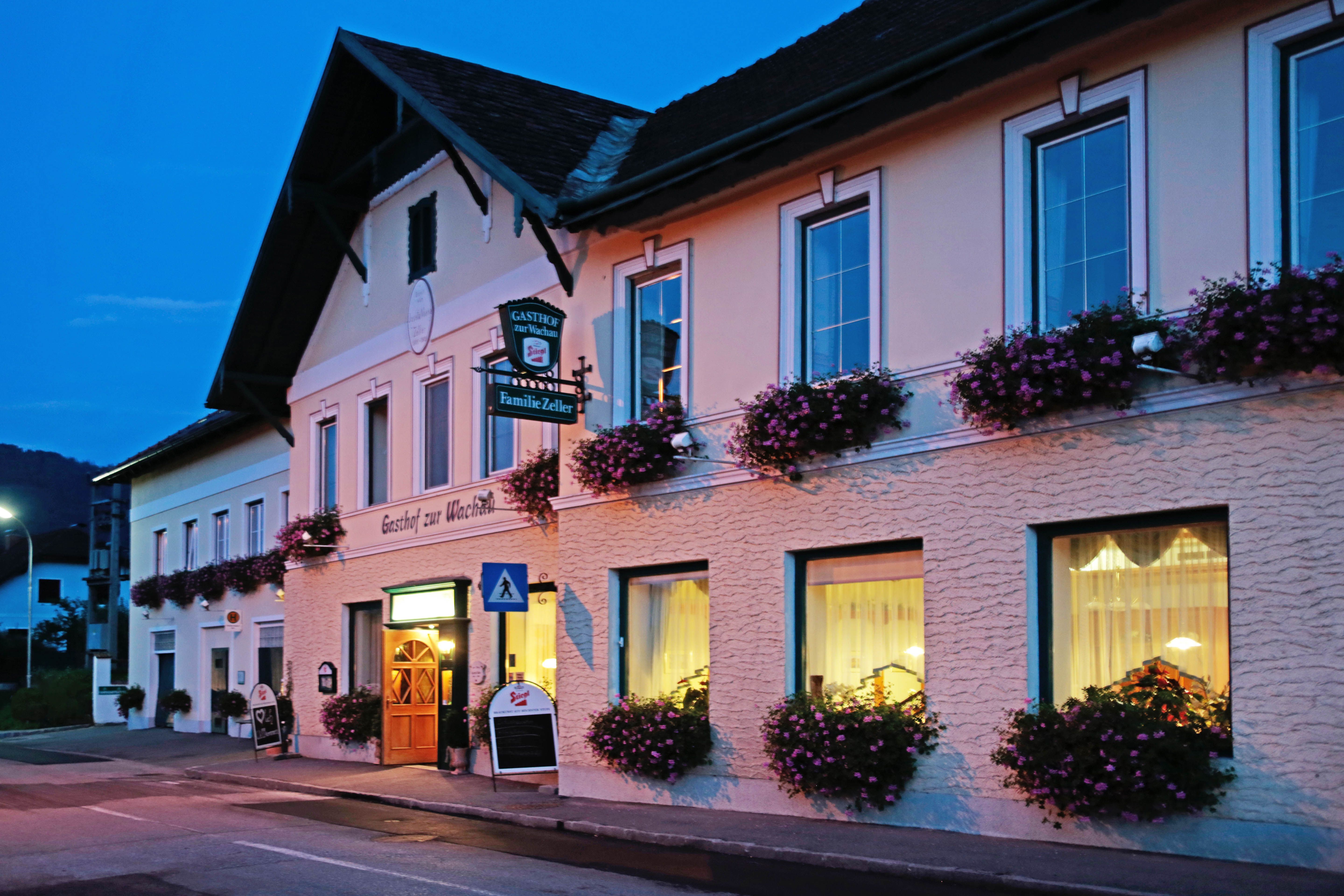 A traditional inn with windows decorated with flowers at dusk.