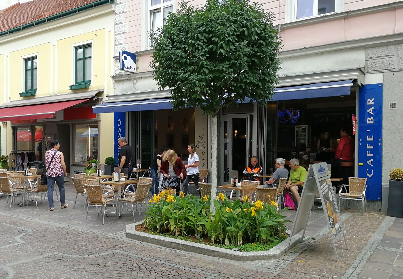 Coffee house from the outside with blue awning and tree in front of it