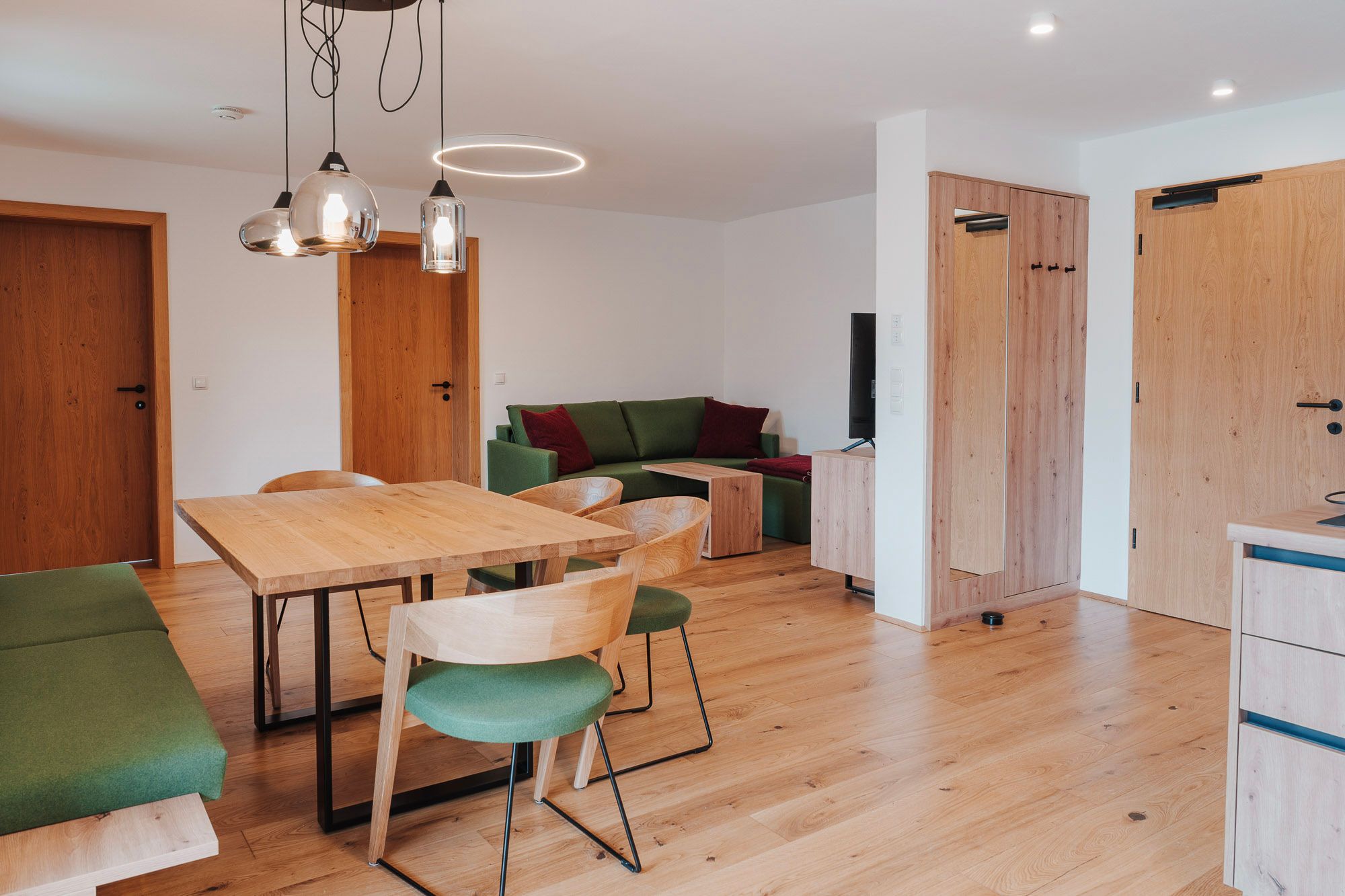 Modern living/dining room with wooden furniture and green accents.
