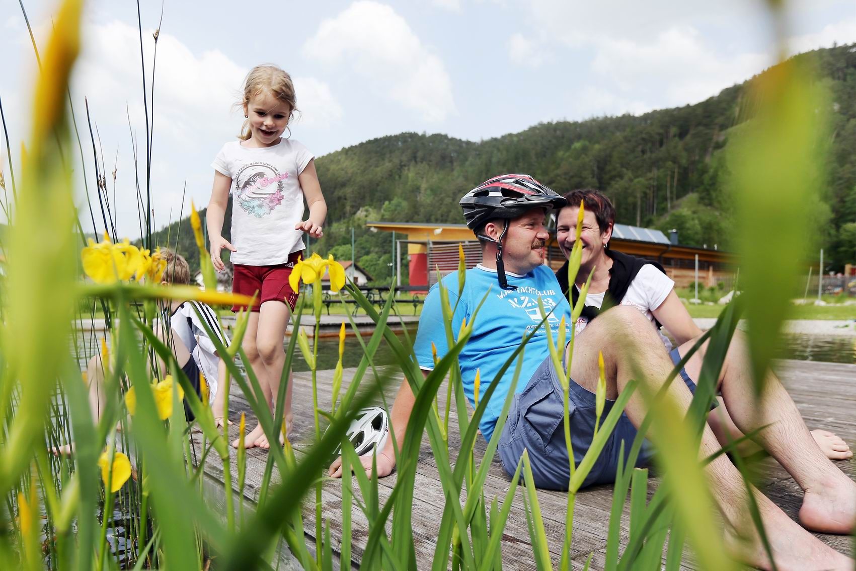 Family relaxing on a jetty at the Türnitz natural adventure pool.
