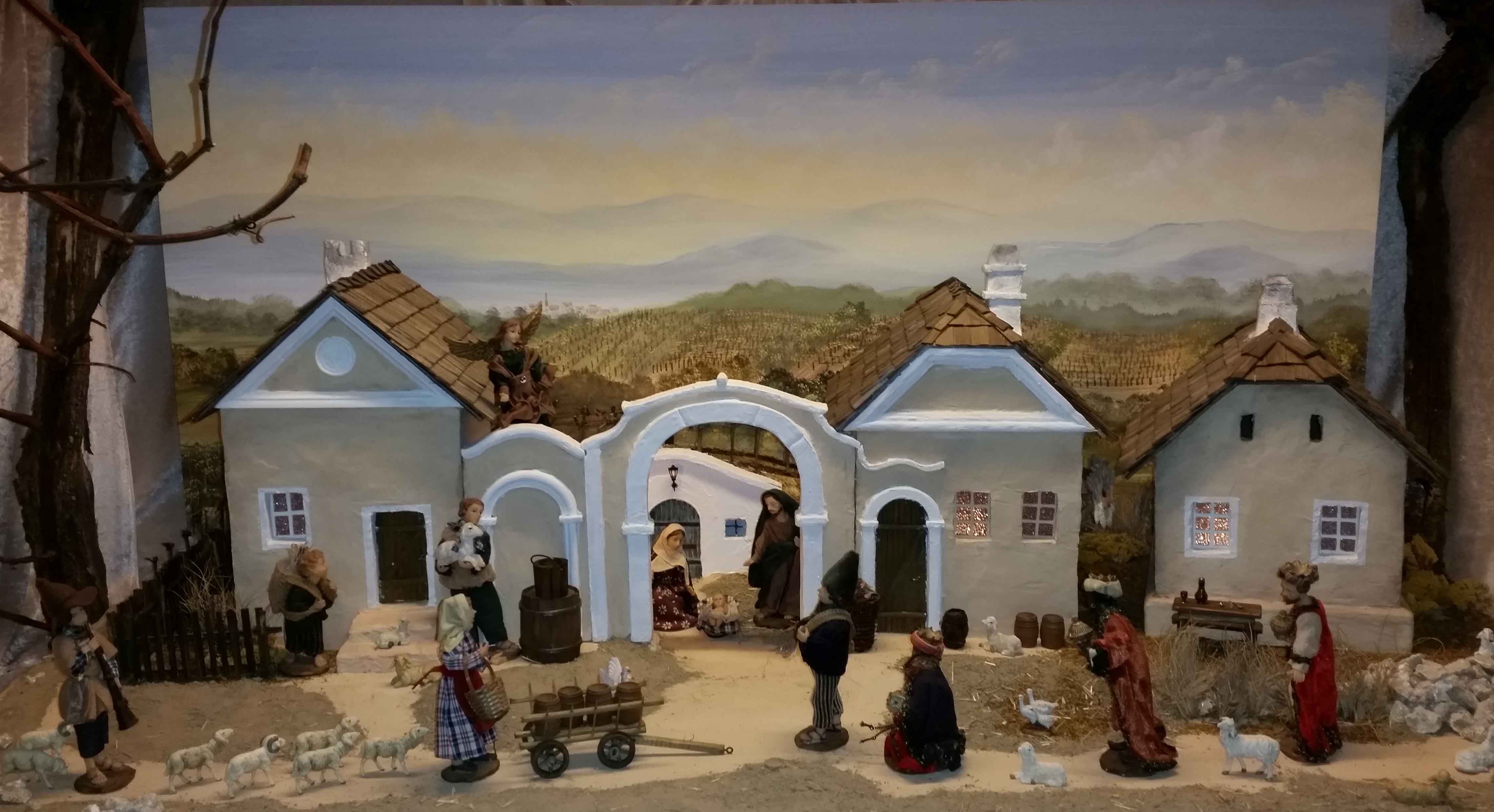 Christmas crib with figures and buildings in a rural setting.