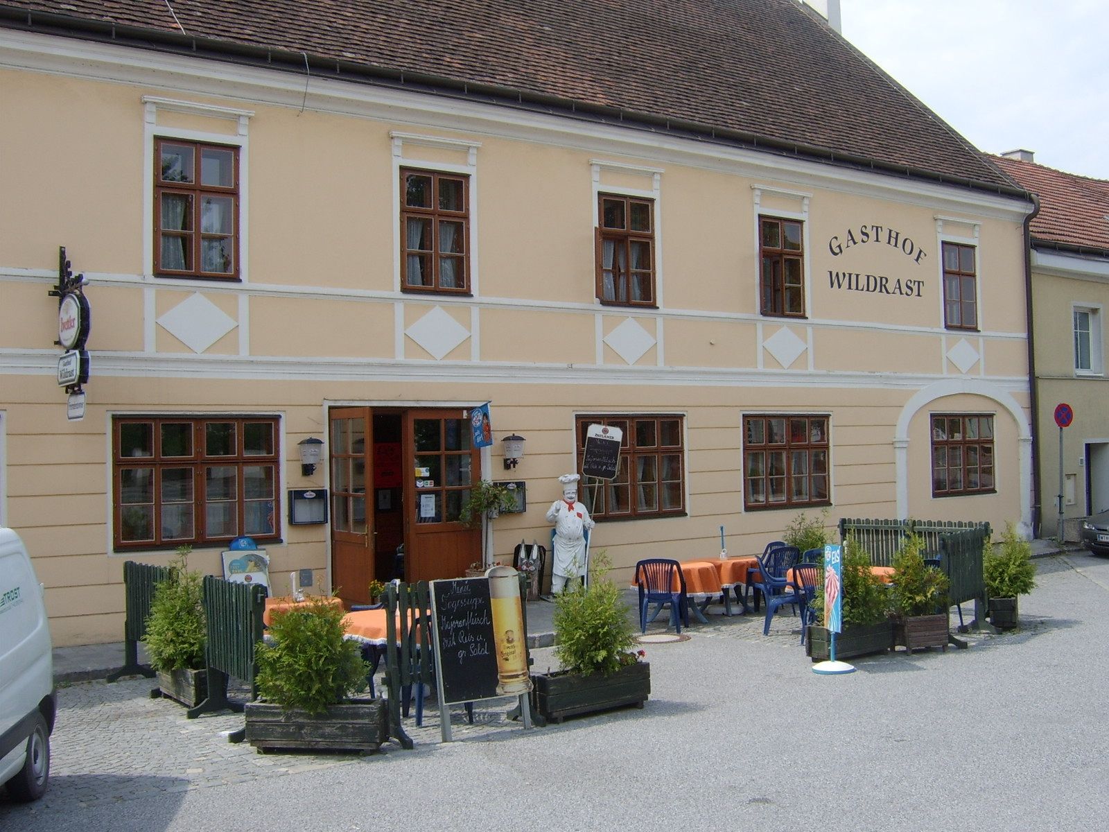 Exterior view of the Wildrast inn with tables and chairs outside.