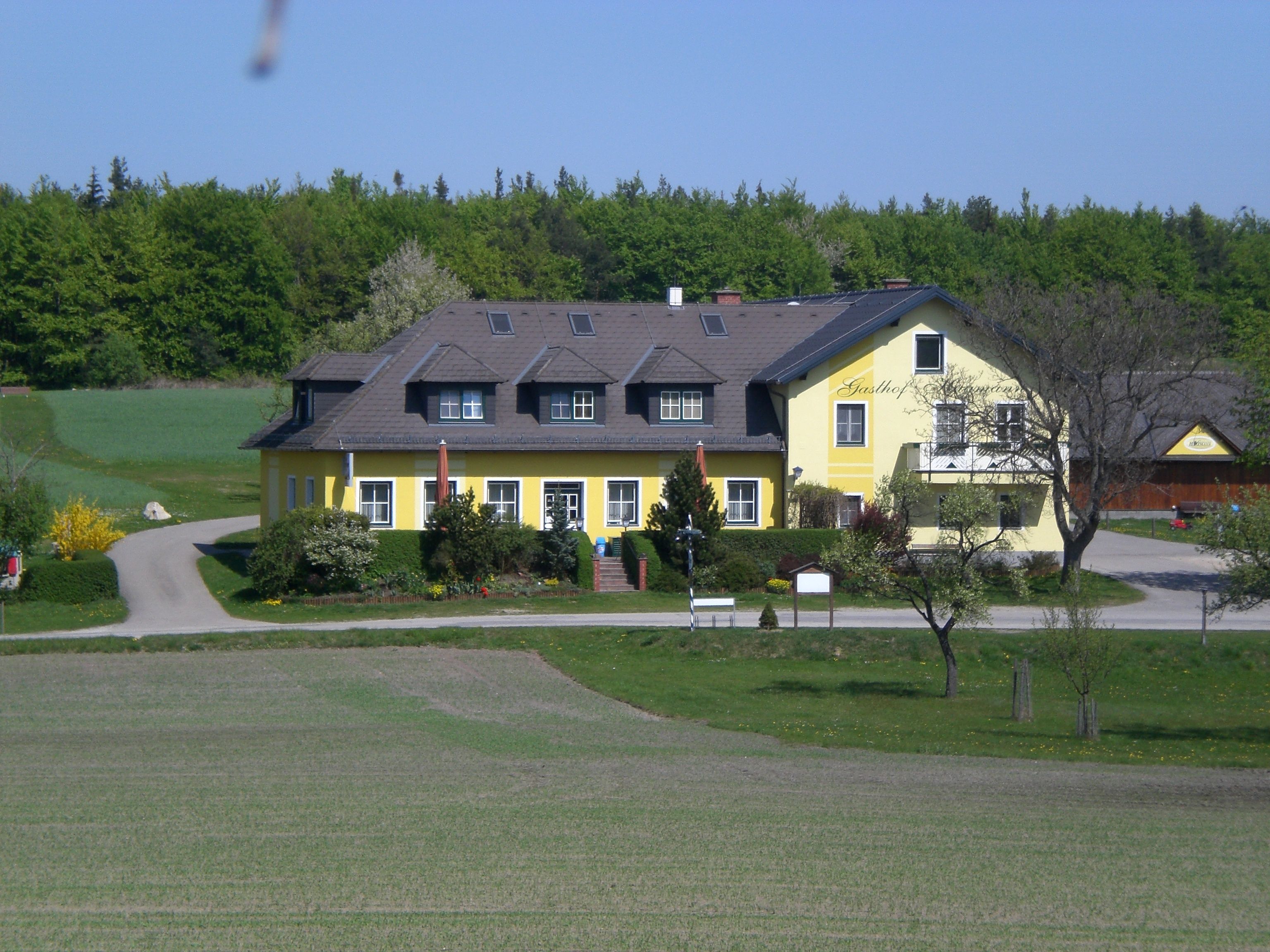A yellow inn in a rural setting with trees and meadows.
