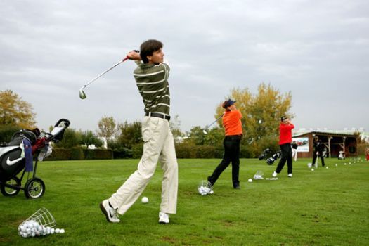 People playing golf on a driving range.