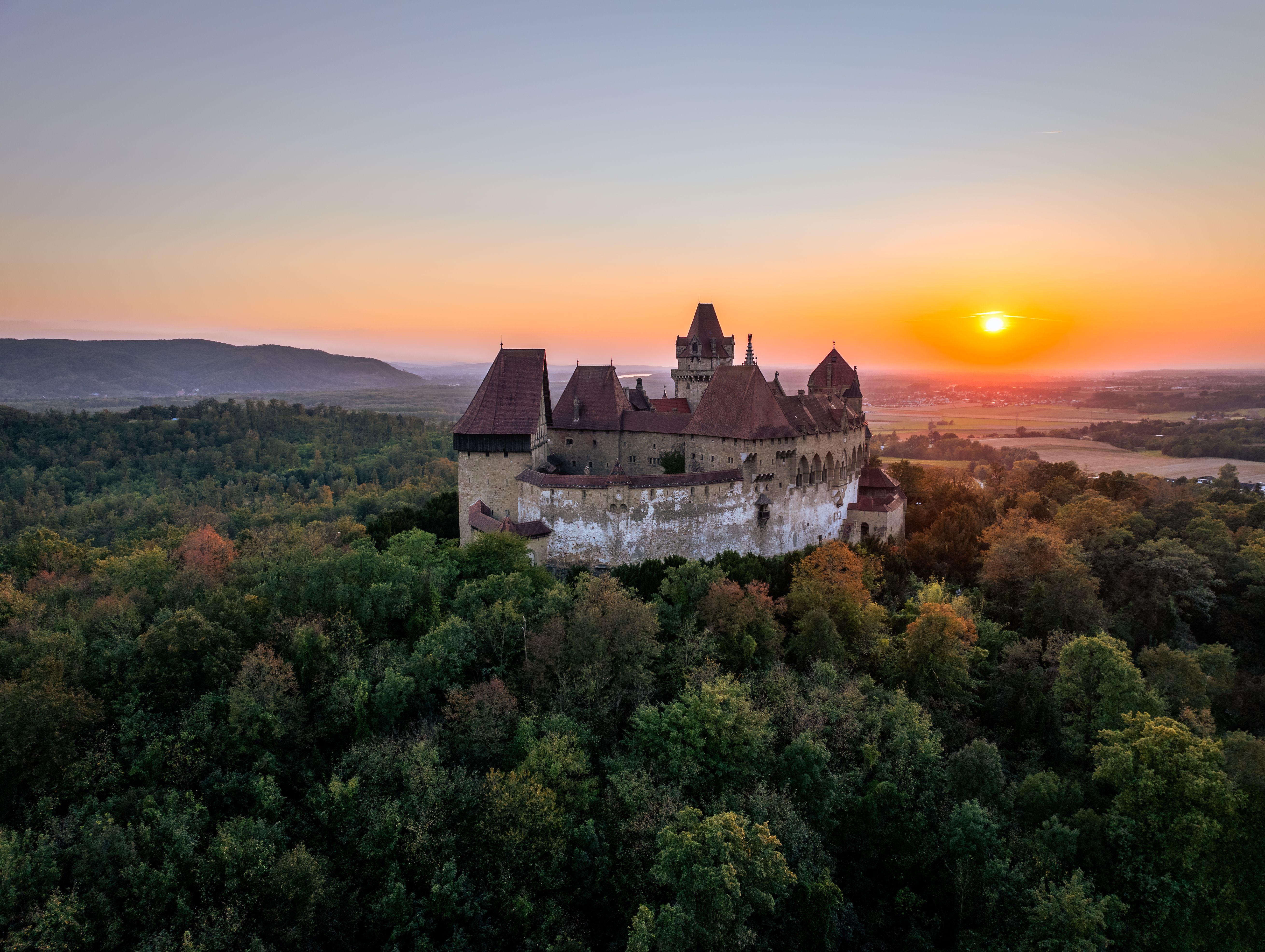 Die majestätische Burg erhebt sich stolz über die sanften Hügel des Weinviertels, während die untergehende Sonne den Himmel in ein warmes Farbenspiel taucht. Umgeben von dichten Wäldern und malerischen Landschaften, lädt dieser Ort dazu ein, die Schönheit der Natur und die Geschichte der Region zu entdecken.