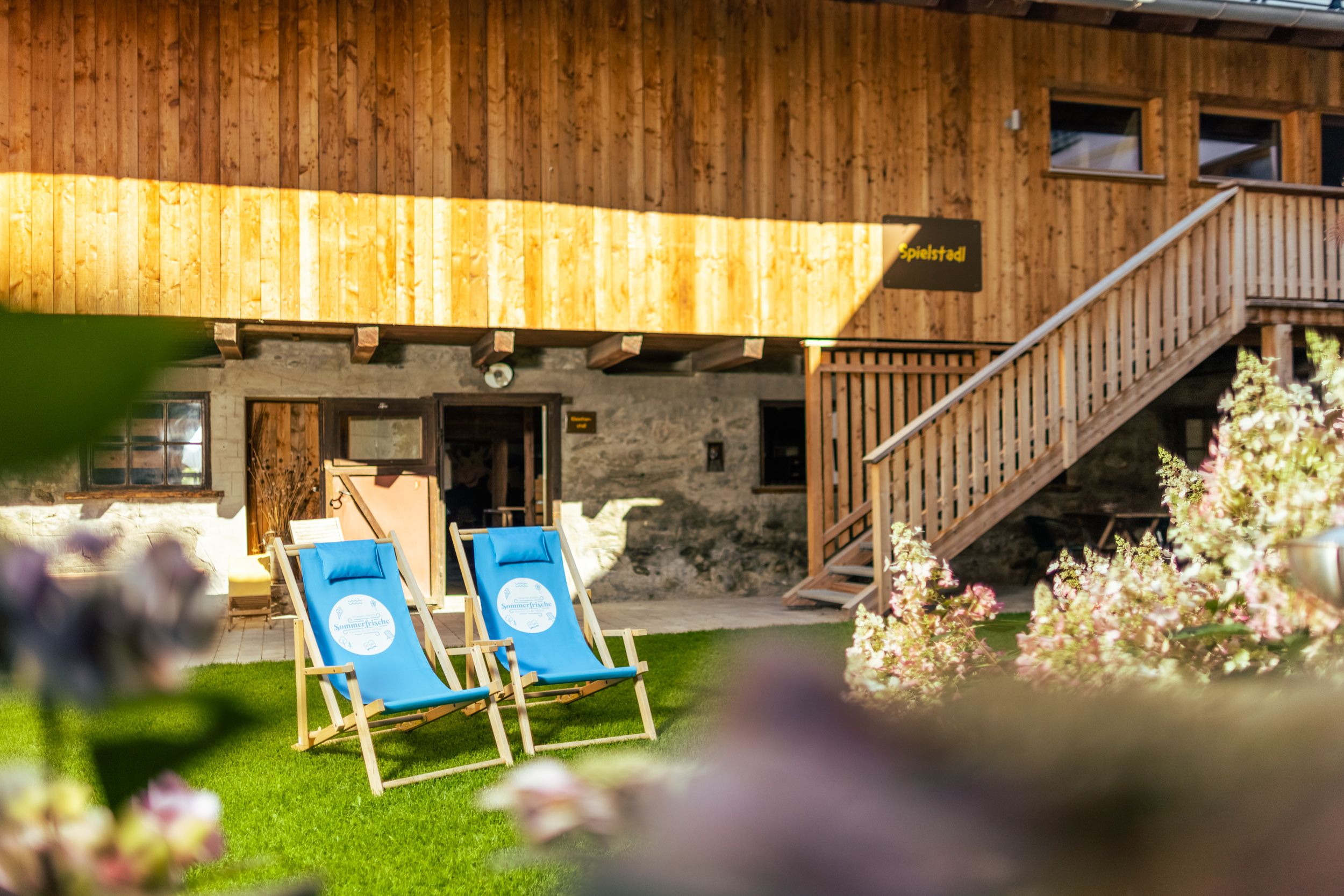 Two blue deckchairs on a lawn in front of a rustic wooden building.