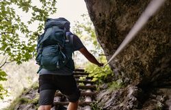 Ein Wanderer erklimmt mit Entschlossenheit die steilen Stufen, umgeben von üppigem Grün und dem beruhigenden Klang der Natur. Die frische Bergluft und die Aussicht auf die majestätischen Gipfel versprechen ein unvergessliches Abenteuer in den Wiener Alpen.