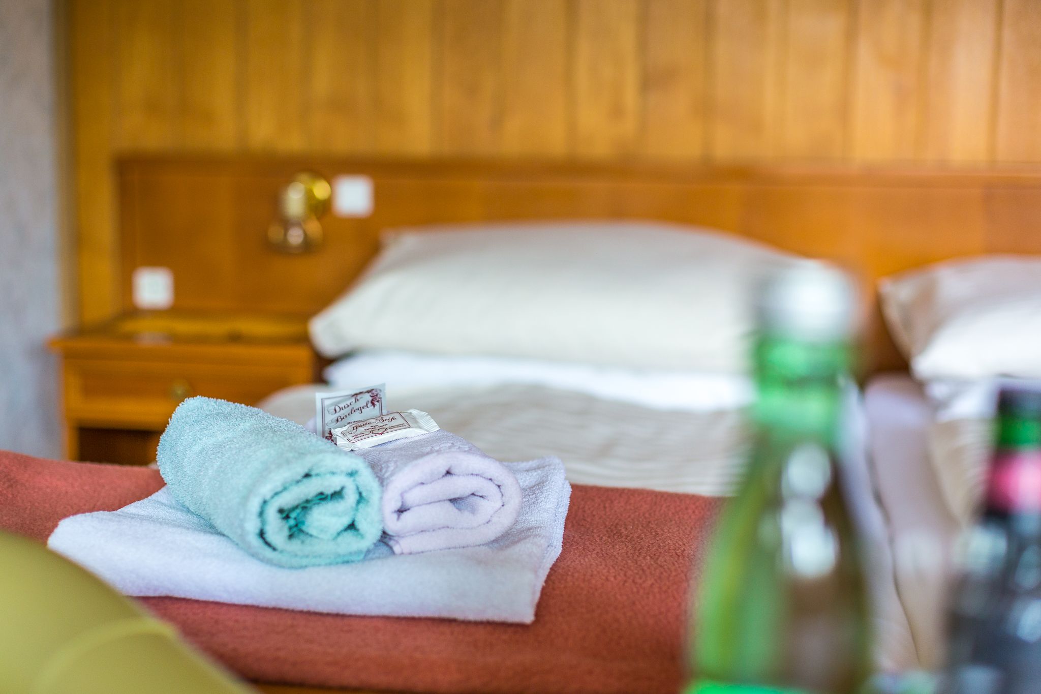Hotel room with bed, towels and water bottles.