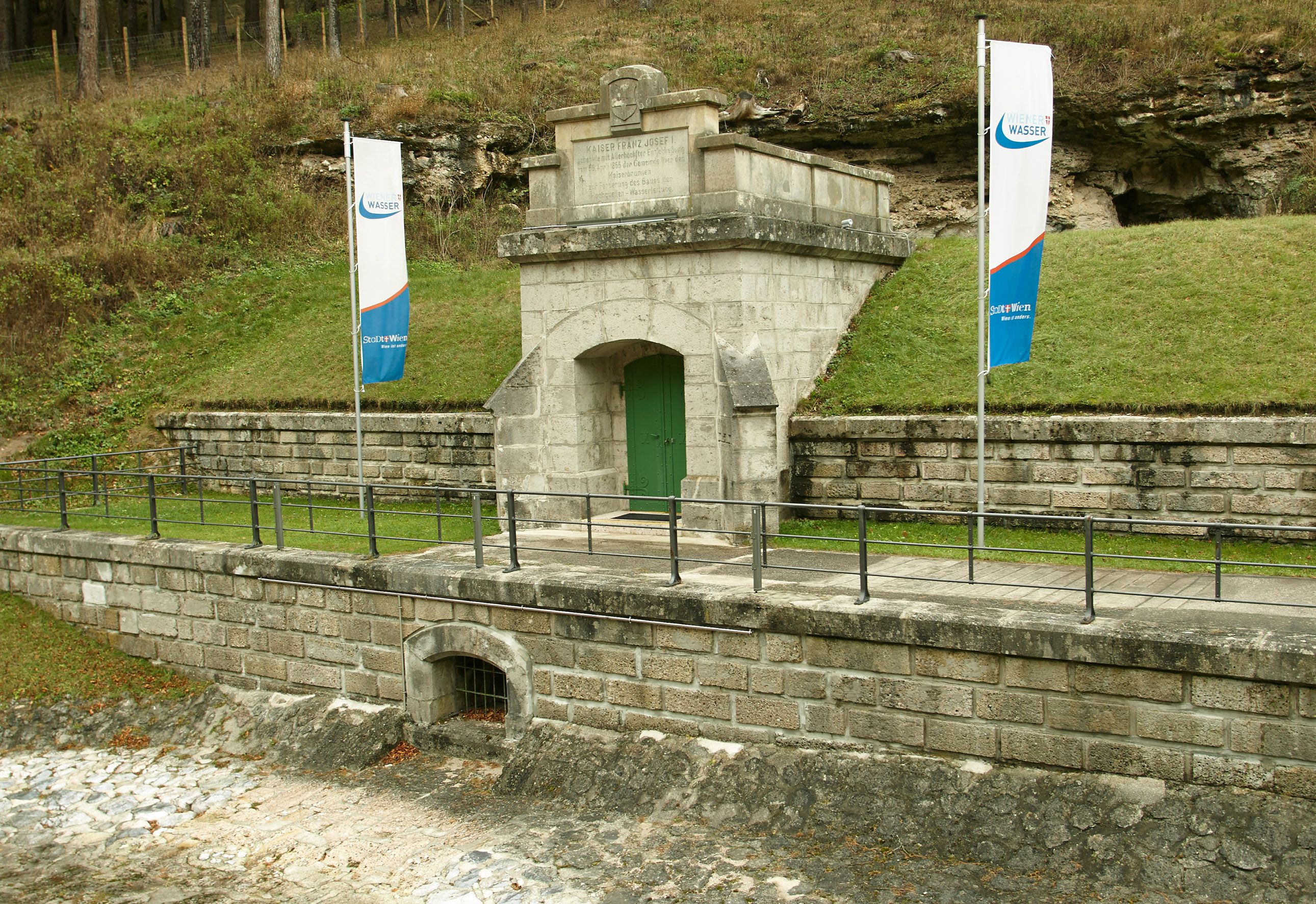 Entrance to the Kaiserbrunn water pipe museum with two flags.