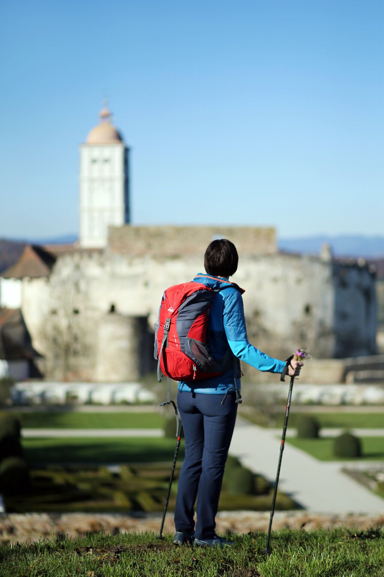 A hiker enjoys the breathtaking view of the majestic Schallaburg, while the rolling hills of the Melk Alpine foothills glow in the background. The clear air and tranquil surroundings invite you to experience the beauty of nature to the full.