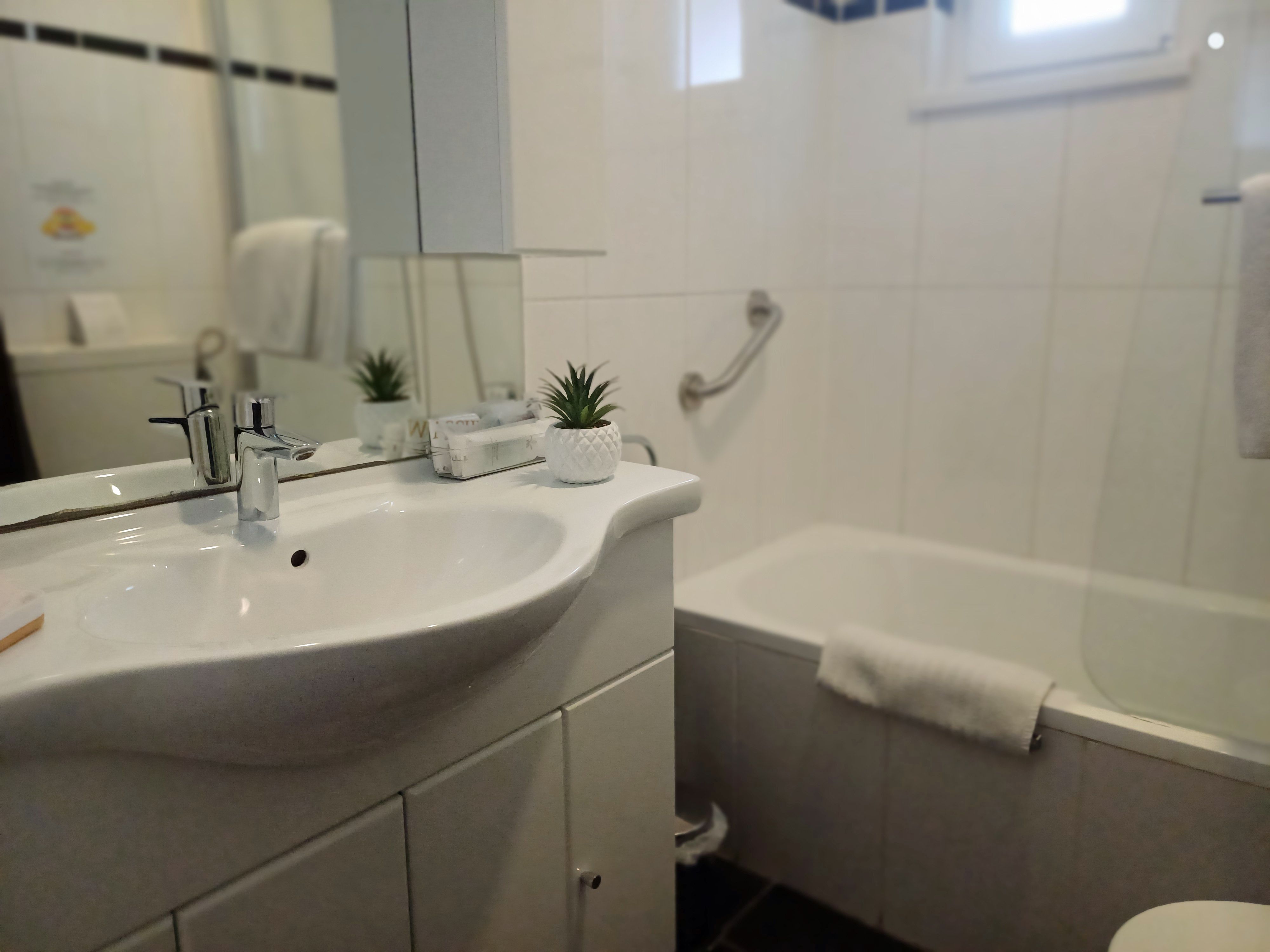 Bathroom with washbasin, mirror, bathtub and towel.