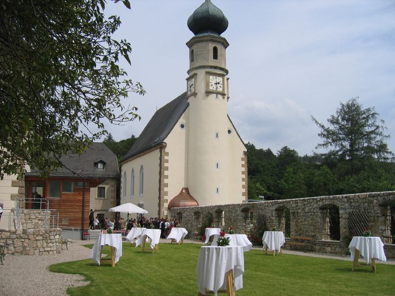Church with tower and garden with bar tables, wedding scene.
