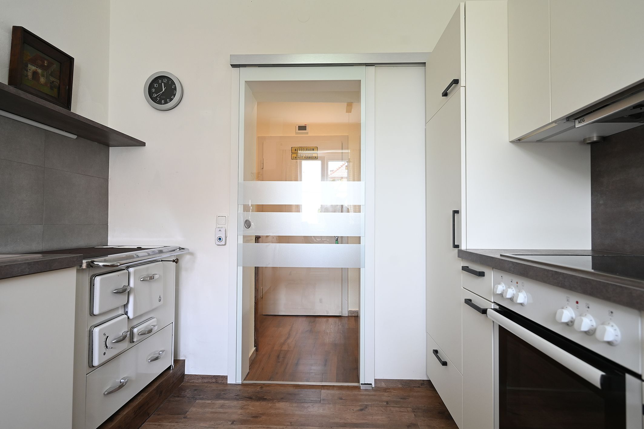 Modern kitchen with stove, cupboards and glass door.