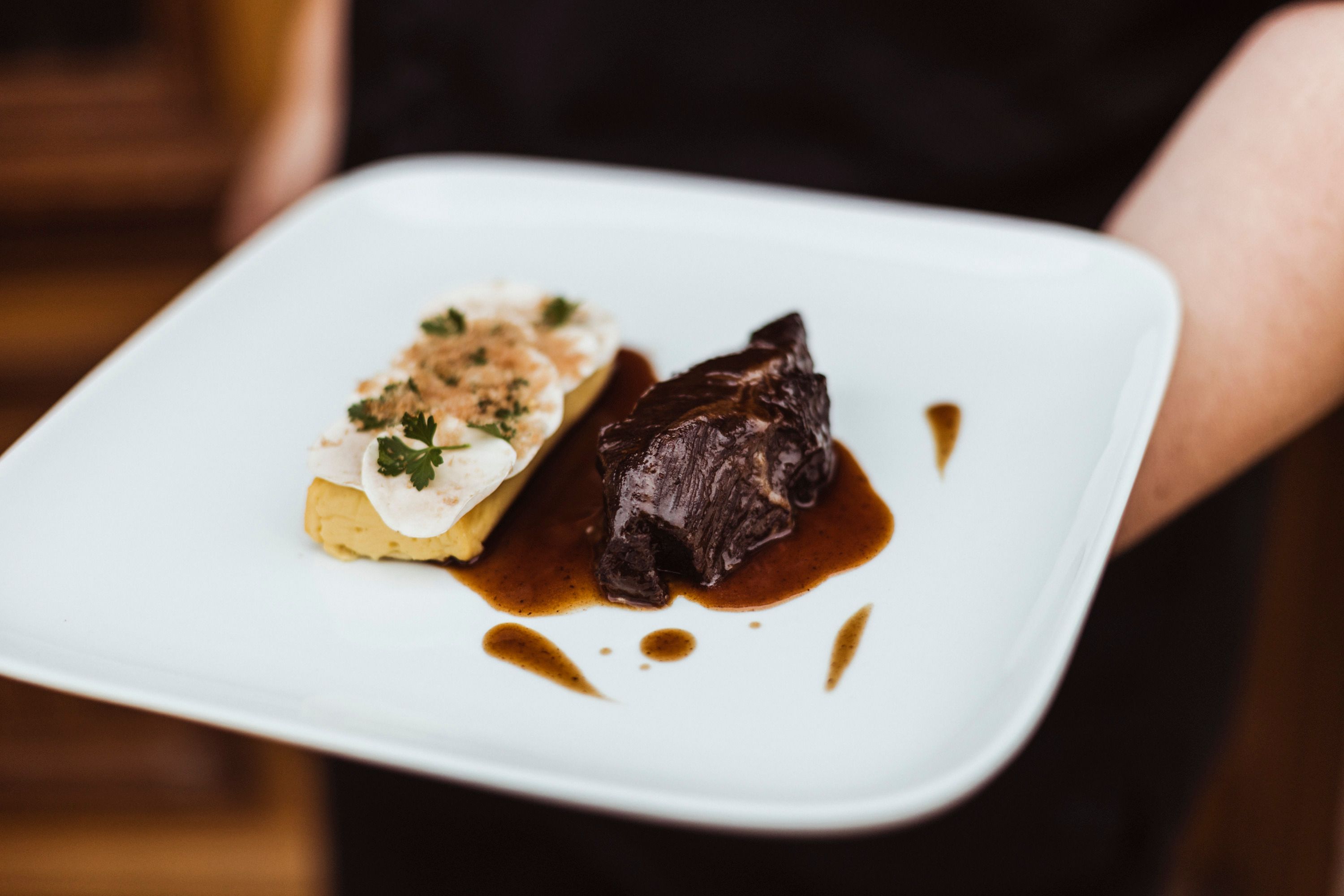 A plate of beef cheeks in sauce and mushrooms on potato soufflé.