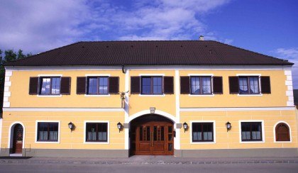 Yellow two-story building with brown shutters and a large wooden gate in the middle.