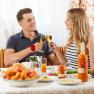 A couple toast with champagne glasses at breakfast, surrounded by fruit and drinks on a laid table.