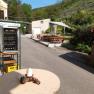 An outdoor area with a drinks fridge, tables and benches next to a vineyard.