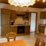 Kitchen with wooden furniture, dining table and chairs, stove, sink and dishwasher.