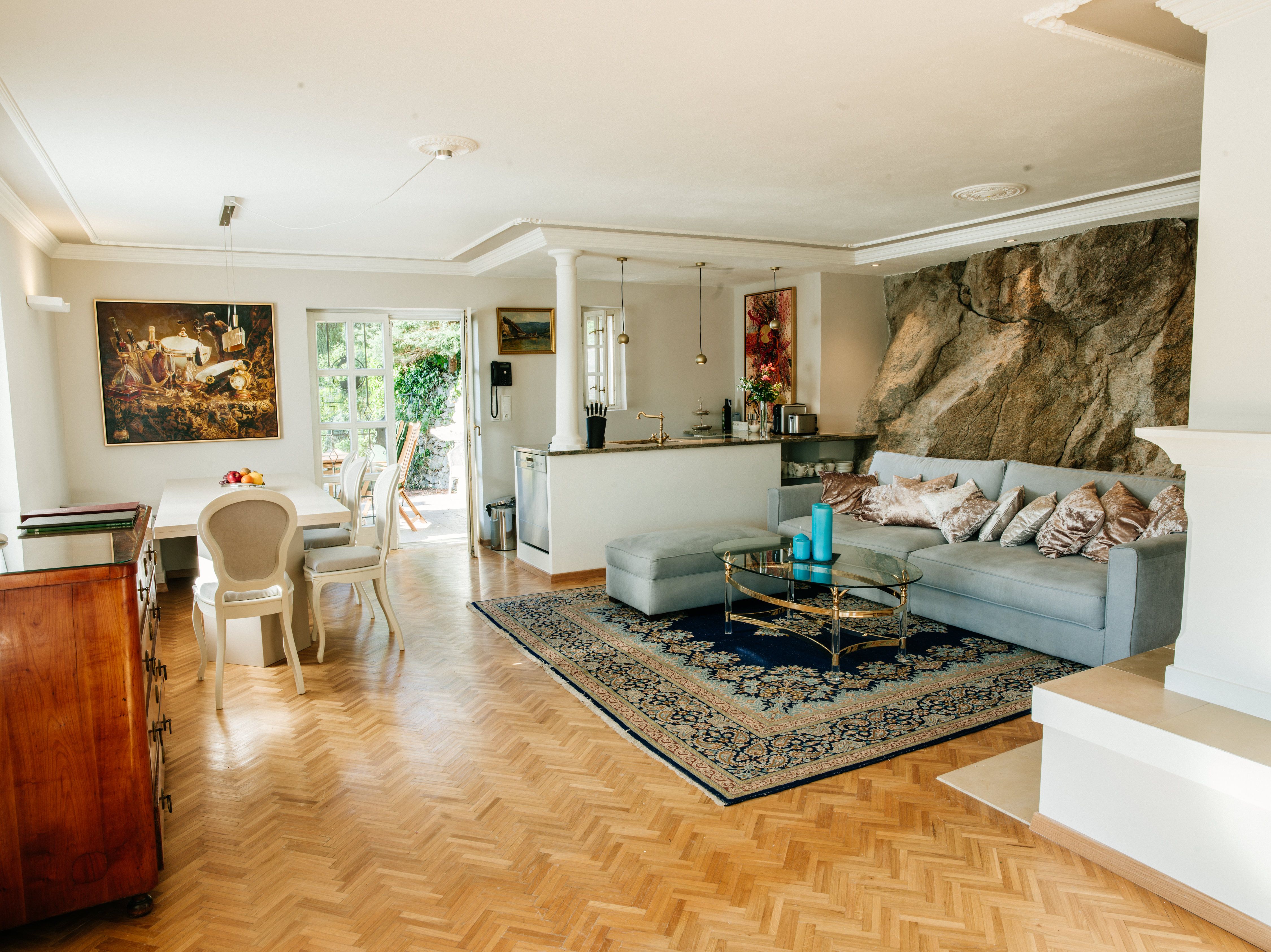 Elegant living room with parquet floor, blue couch, glass table and painting on the wall.