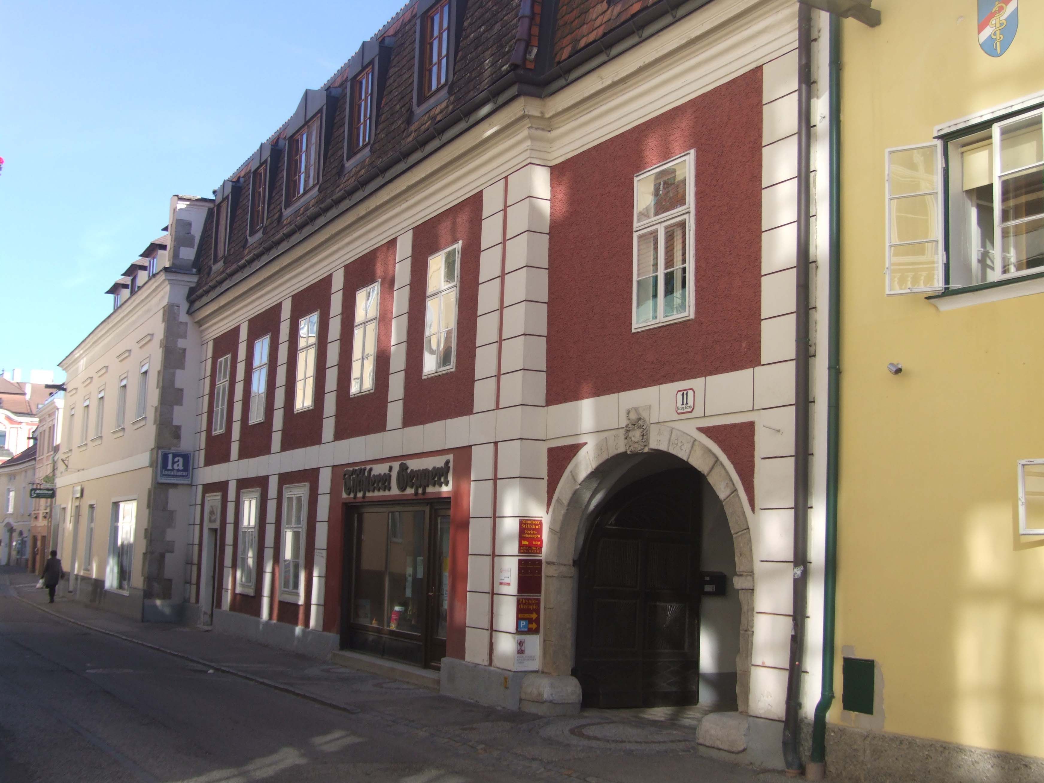 Historic building with red façade and archway in a street.