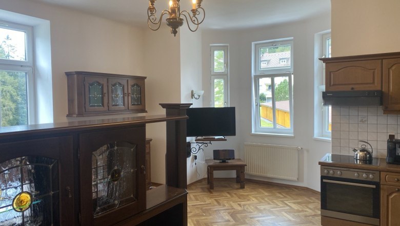 Interior view of a kitchen with wooden furniture, a chandelier and large windows.