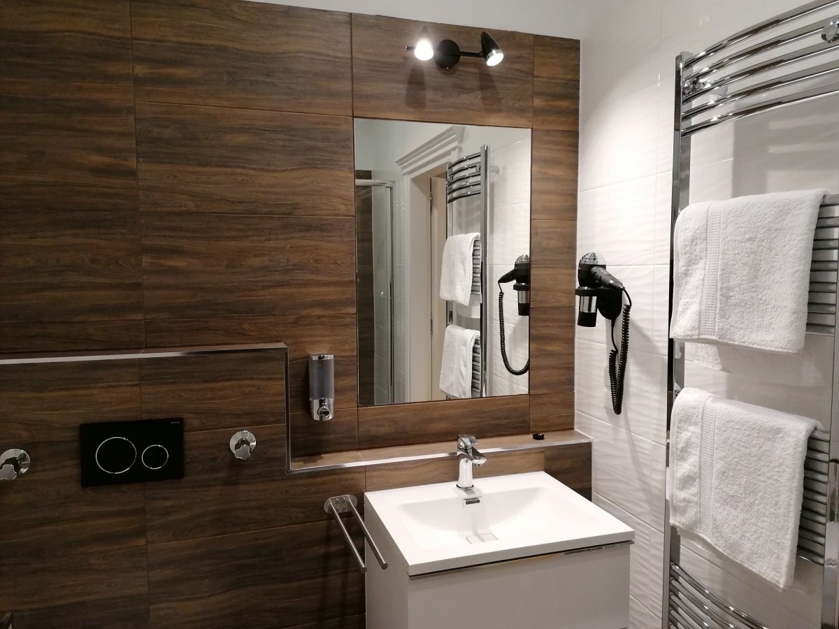 Modern bathroom with wooden paneling, washbasin, mirror, towel rail and hairdryer.