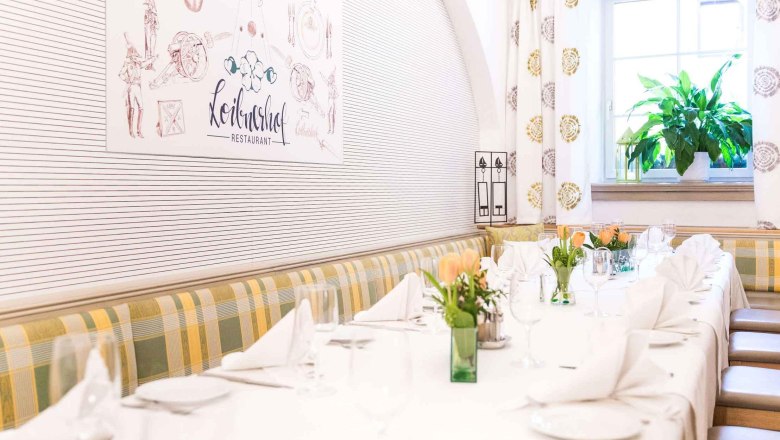 Elegant restaurant interior with table setting, flowers and window with plant.