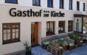 Facade of an inn with wooden pallet furniture in front of the entrance.