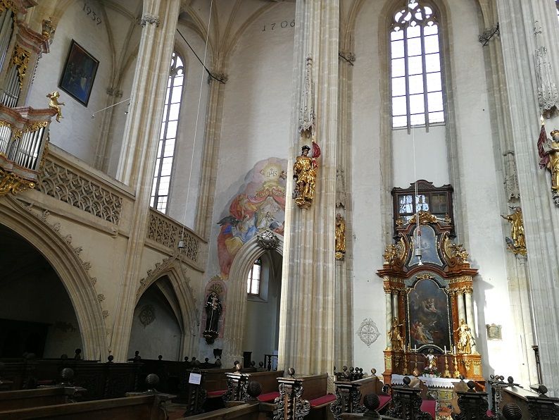 Interior view of the Piarist Church with altar, frescoes and high windows.